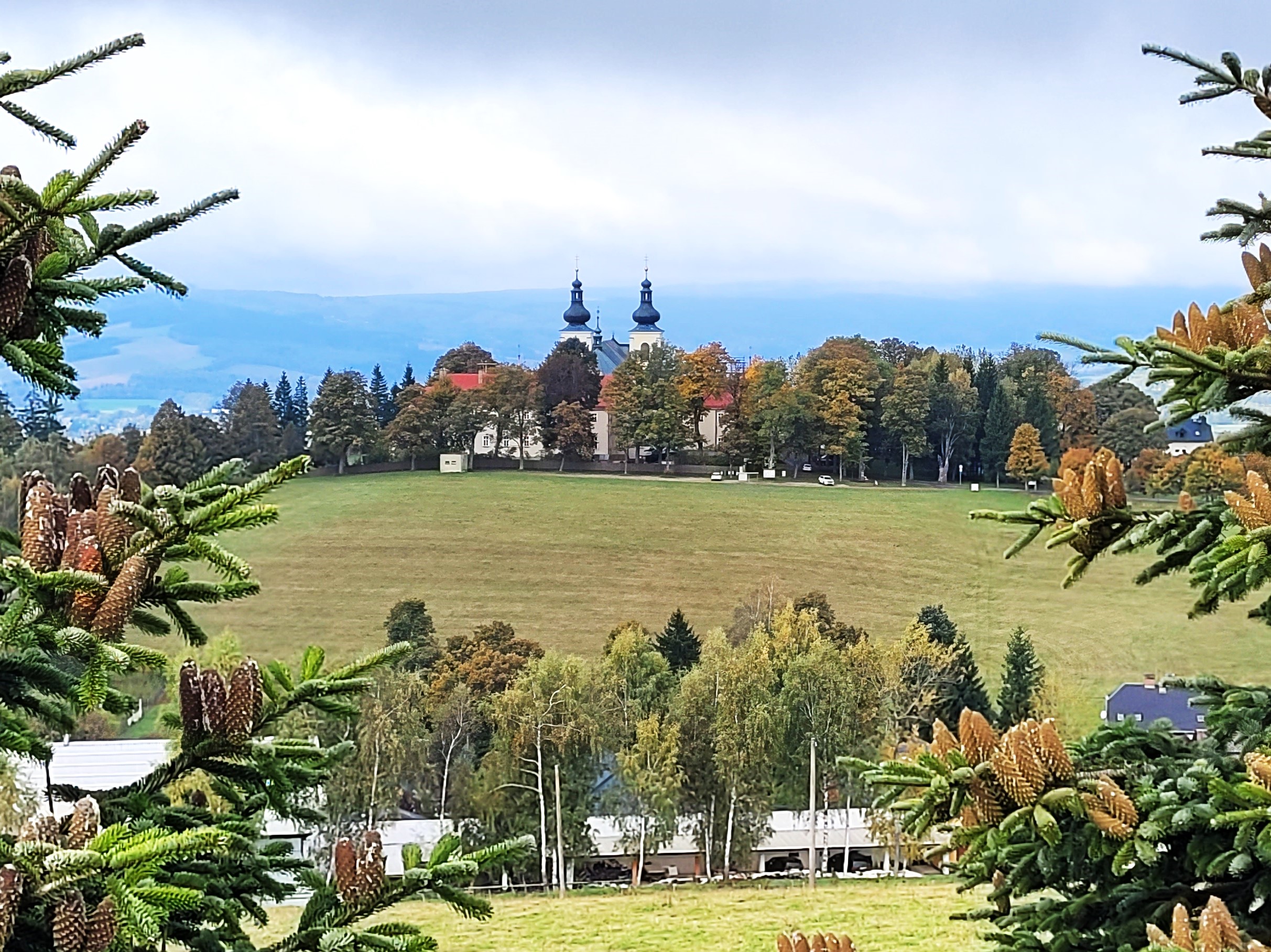 Pohled na klášter na Hořem Matky Boží, po stranách snímku jsou jedle se šiškami.